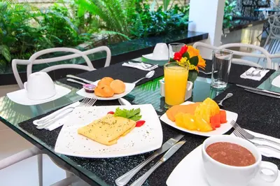 a table with plates of food and a cup of orange juice at GIO hotel Tama Cartagena in Cartagena de Indias