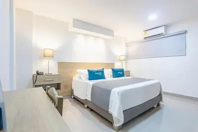a bedroom with a large bed with blue pillows at Hotel Ancor in Sincelejo