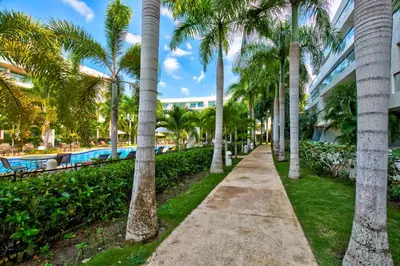 a walkway through palm trees next to a swimming pool at Estelar Playa Manzanillo - All inclusive in Cartagena de Indias