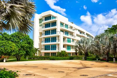 a large white building with palm trees in front of it at Estelar Playa Manzanillo - All inclusive in Cartagena de Indias