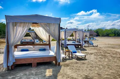 a group of four beds and chairs on a beach at Estelar Playa Manzanillo - All inclusive in Cartagena de Indias