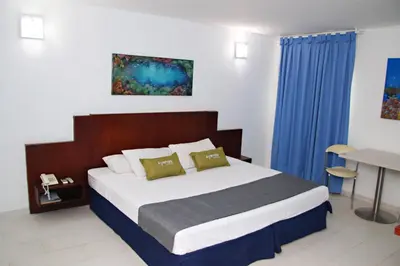 a bedroom with a large bed with blue curtains at Ayenda 1801 El Oceano in Cartagena de Indias