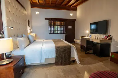 a bedroom with a bed and a desk and a television at GHL Collection Armería Real Hotel in Cartagena de Indias