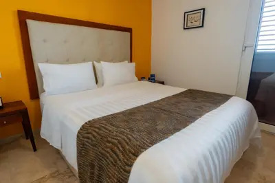 a bedroom with a large bed with white sheets at GHL Collection Armería Real Hotel in Cartagena de Indias