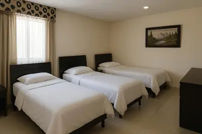 a room with three beds with white sheets at Hotel Continental Express in Barranquilla
