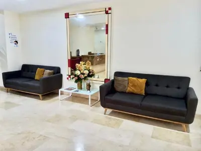 a living room with two black couches and a mirror at Hotel Continental Express in Barranquilla
