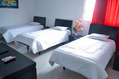 a room with three beds and a table with flowers at Hotel Continental Express in Barranquilla