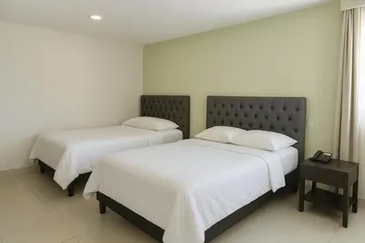 two beds with white sheets in a room at Hotel Continental Express in Barranquilla