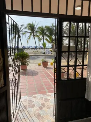 an open door leading to a patio with palm trees at Habitación I frente a la playa ( Bocagrande ) in Cartagena de Indias