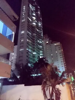 a tall building with palm trees in a city at night at Habitación I frente a la playa ( Bocagrande ) in Cartagena de Indias