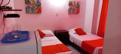 a room with two beds with red and white sheets at Habitación I frente a la playa ( Bocagrande ) in Cartagena de Indias
