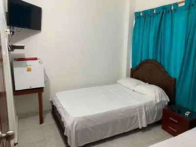 a bedroom with a bed with a blue curtain at Habitación I frente a la playa ( Bocagrande ) in Cartagena de Indias
