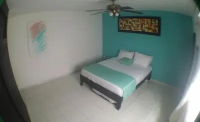 a bedroom with a bed with a green wall at QuillaHost Tropical Apartment in Barranquilla