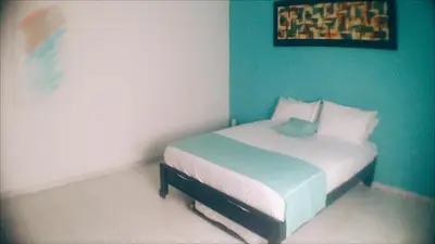 a small bed in a room with a green wall at QuillaHost Tropical Apartment in Barranquilla