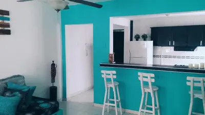 a kitchen with three bar stools and a blue wall at QuillaHost Tropical Apartment in Barranquilla