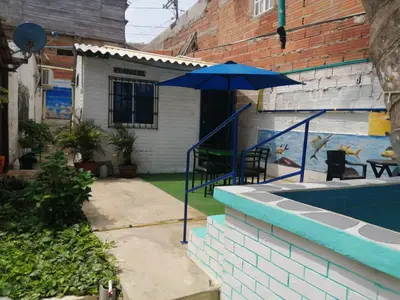 a patio with a blue umbrella and a pool at Villa mar in Puerto Colombia