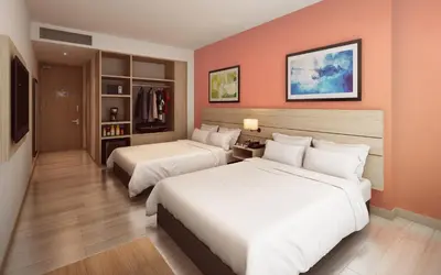 two beds in a hotel room with orange walls at Holiday Inn Express Cartagena Manga by IHG in Cartagena de Indias