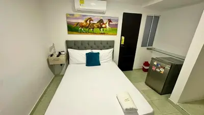 a bedroom with a white bed with a blue pillow at Hotel Casa Paraiso in Barranquilla