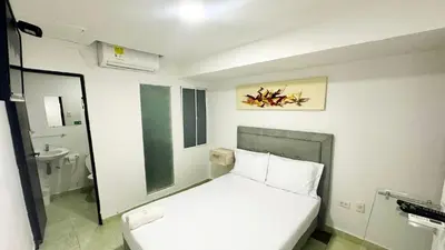 a small bedroom with a white bed and a bathroom at Hotel Casa Paraiso in Barranquilla
