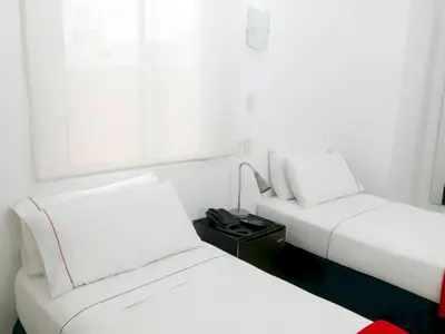 two beds in a hotel room with white walls at Zalmedina Hotel in Cartagena de Indias