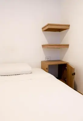 a bedroom with a white bed and a wooden shelf at Santuario Getsemani Hostel in Cartagena de Indias