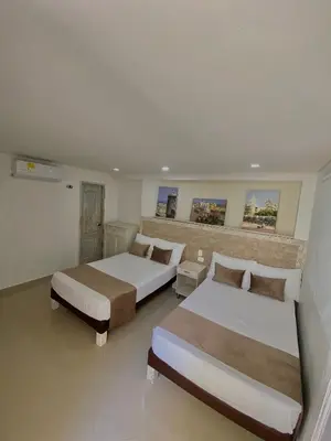 a bedroom with two beds and a brick wall at Hotel La Magdalena in Cartagena de Indias