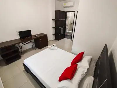 a bedroom with a bed with red pillows and a desk at Hotel Or Cartagena in Cartagena de Indias