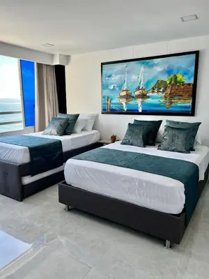 two beds in a bedroom with a large painting on the wall at Palmera Beach in Cartagena de Indias