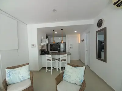 a living room with two chairs and a kitchen at Morros Vitri Cartagena in Cartagena de Indias