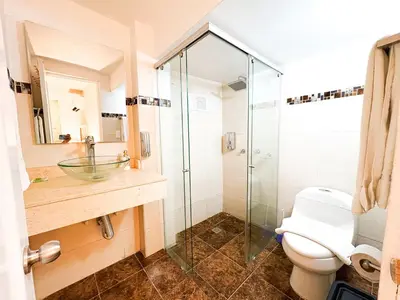 a bathroom with a glass shower and a toilet at Hotel AT THE PARK in Cartagena de Indias