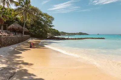 a person sitting on a beach next to the ocean at Hotel San Pedro de Majagua in Isla Grande