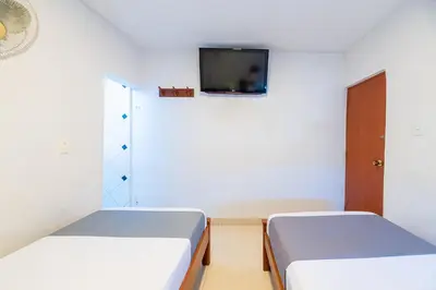 two beds in a room with a tv on the wall at Hotel Nuevo Yalu in Barranquilla