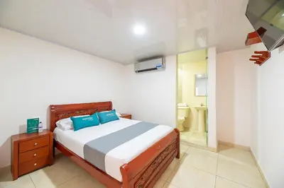 a bedroom with a bed with blue pillows and a bathroom at Hotel Nuevo Yalu in Barranquilla