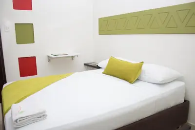 a bedroom with a white bed with a yellow pillow at Terra Toscana Hotel in Mangue