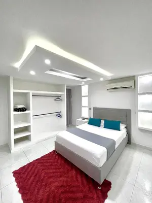 a bedroom with a large bed and a red rug at Hostal Casa Tropicalia in Barranquilla