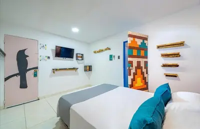 a bedroom with a bed and a wall with art at Hostal Casa Tropicalia in Barranquilla