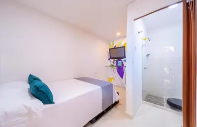 a white bedroom with a bed and a shower at Hostal Casa Tropicalia in Barranquilla