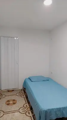 a bedroom with a blue bed and a rug at Hostal Casa Tropicalia in Barranquilla