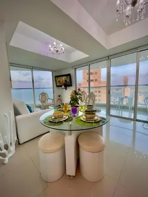 a dining room with a glass table and stools at Beach front Apartament in Cartagena de Indias