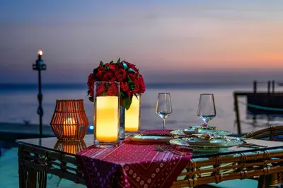 a table with a vase of roses and two wine glasses at Hotel Isla del Encanto in Baru