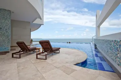 a swimming pool with two chairs and the ocean at Palmetto Eliptic 4003 in Cartagena de Indias