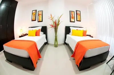 a bedroom with two beds with orange and yellow pillows at Hotel Atlantic Lux in Cartagena de Indias
