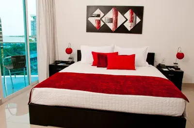 a bedroom with a large bed with red pillows at Hotel Atlantic Lux in Cartagena de Indias