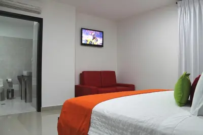 a bedroom with a bed and a red chair at Hotel Atlantic Lux in Cartagena de Indias