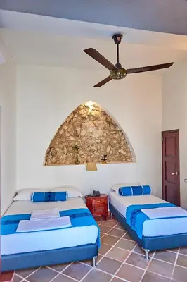 two beds in a room with a stone wall at Cartagena Legends in Cartagena de Indias