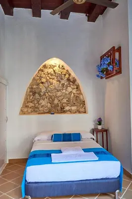 a bedroom with a bed with a stone wall at Cartagena Legends in Cartagena de Indias