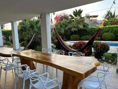a hammock on a patio with a table and chairs at Villa Las Marias in Santa Veronica