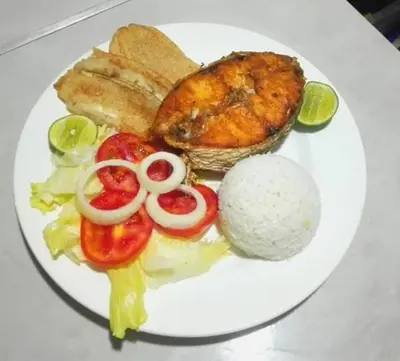 a plate of food with meat and vegetables and rice at La Roca Coveñas Apartamentos in Coveñas