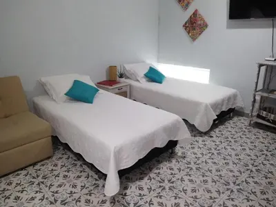 two beds in a room with a chair and a couch at Casa Anita in Cartagena de Indias