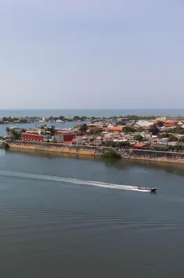 a boat on a river with a city in the background at Bahia 79 Apartasuites Cerca al Centro in Cartagena de Indias